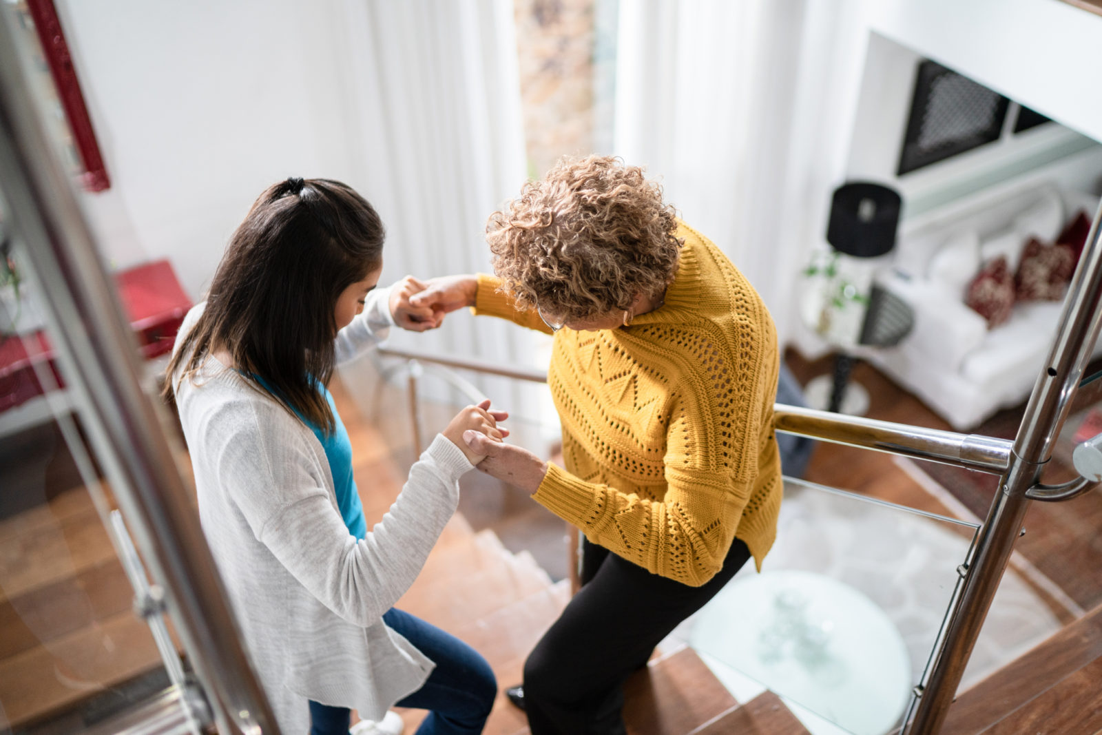 Nurse supporting senior patient walking or moving up the stairs at home