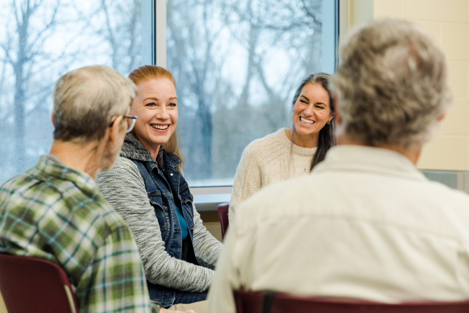 A multigenerational group of people sit near each other as they participate in group therapy