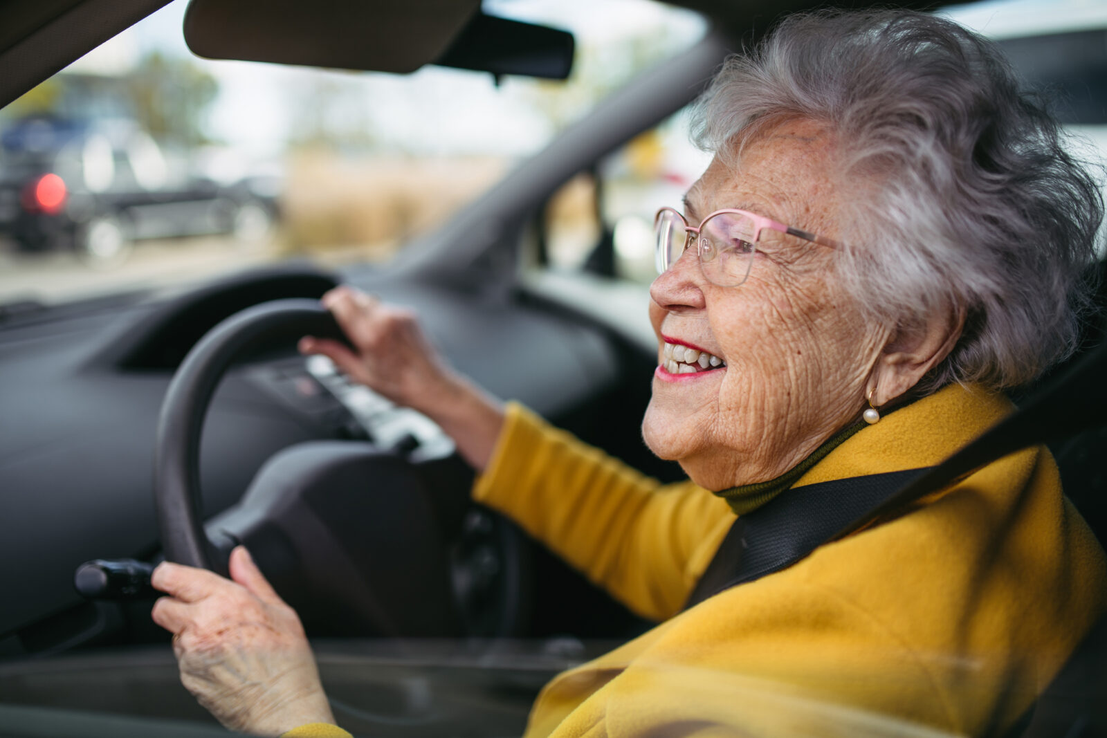 Happy senior woman driving car alone